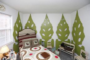 Indianapolis apartment for rent - a bedroom with a bed and a wall painted with trees