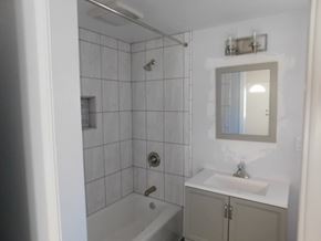 San Diego apartment for rent - A white bathroom with a white tub, sink, and a mirror.