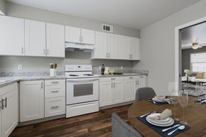Omaha apartment for rent - a kitchen with white appliances and white cabinets and a dining table