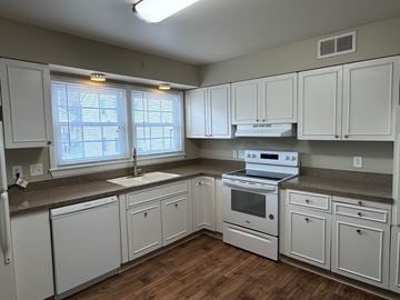 Omaha apartment for rent - A kitchen with white cabinets and a stove top oven.