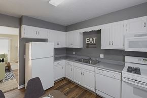 Omaha apartment for rent - an image of a kitchen with white cabinets and a sink and refrigerator