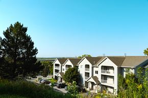 Council Bluffs apartment for rent - A large white building with a green tree in front of it.