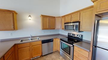 West Fargo townhouse for rent - a kitchen with stainless steel appliances and wooden cabinets