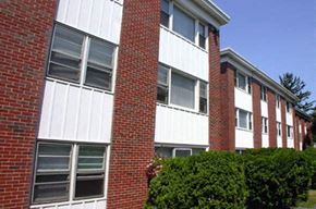 Cranston apartment for rent - an apartment building with a red brick facade and green bushes