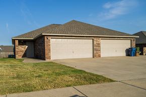 Gentry apartment for rent - a garage door on a brick house with a driveway