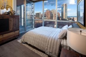 Chicago apartment for rent - A bedroom with a large bed and a view of the city.
