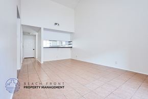 Long Beach apartment for rent - A spacious room with tiled flooring and a logo for Beach Front Property Management in the corner.