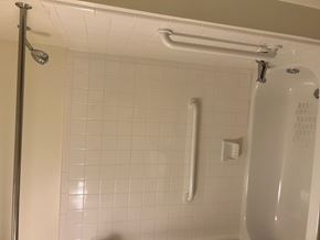 Gwynn Oak apartment for rent - A white tiled shower with a white shower head and hand held shower.