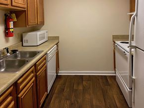 Mobile apartment for rent - kitchen with white appliances and hardwood-style floors
