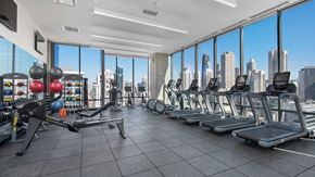 Chicago apartment for rent - The fitness center at Hubbard221. Various weight machines and free-weights are set on the left. To the right is a row of running and cycling equipment all facing floor-to-ceiling windows. The city is