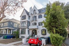 Alameda apartment for rent - A red car is parked in front of a white and black house.