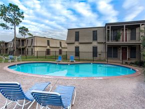 Houston apartment for rent - a resort style pool with blue chairs and apartments in the background