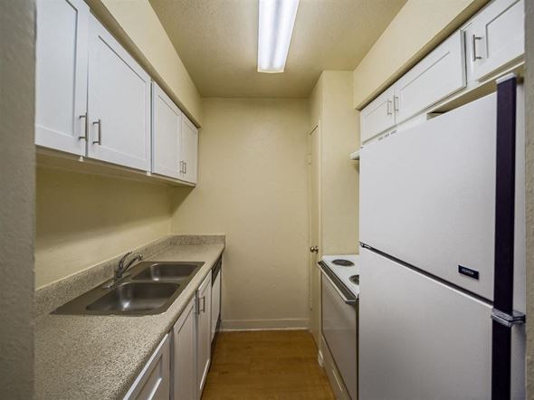 Houston apartment for rent - a kitchen with white cabinets and a sink and a refrigerator
