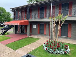 Houston apartment for rent - a building with a red sign and flowers in front of it