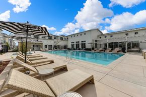 Morgan Hill apartment for rent - Outdoor pool area with tan colored lounge seating and black & white pool-side umbrellas at Morgan Ranch Apartments, Morgan Hill, California
