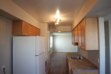 Thompson apartment for rent - A kitchen with a white fridge and wooden cabinets.