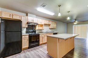 Fargo apartment for rent - a kitchen with wooden cabinets and a black refrigerator