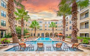 Frisco apartment for rent - an outdoor pool with chairs and palm trees at an apartment building