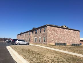 Gentry apartment for rent - a large brick building with cars parked in front of it