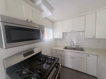 Los Angeles apartment for rent - A kitchen with a black stove top oven and white cabinets.