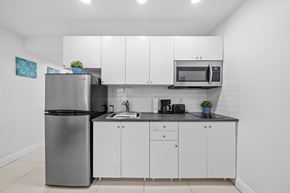 Miami apartment for rent - a kitchen with white cabinets and a stainless steel refrigerator