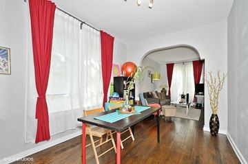 Chicago apartment for rent - a living room with red curtains and a dining room table
