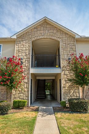 Fort Smith apartment for rent - a stone building with a covered walkway leading to a balcony
