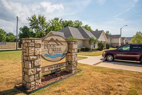 Fort Smith apartment for rent - a car parked in front of a rock retaining wall with a sign