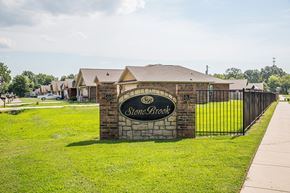 Fort Smith apartment for rent - a stone building with a fence and a sign for stonebrook apartments