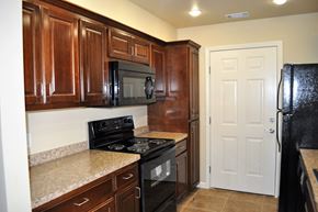 Morrilton apartment for rent - a kitchen with wood cabinets and black appliances and granite counter tops