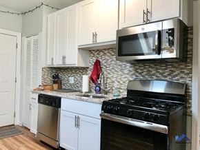 Chicago apartment for rent - a kitchen with white cabinets and a stove and a microwave