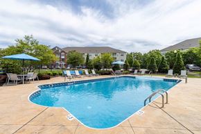 Murrysville apartment for rent - A large outdoor swimming pool surrounded by a fence and lounge chairs.