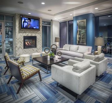 Houston apartment for rent - A modern living room with a fireplace and a television mounted above it.