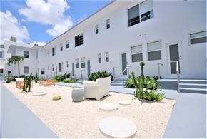 Miami Beach apartment for rent - a large white building with a courtyard with chairs and tables