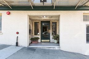 San Francisco apartment for rent - A white building with a black door and a red sign on the wall.
