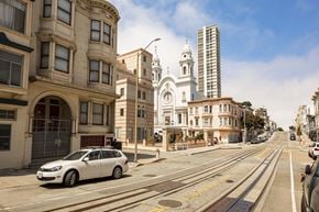 San Francisco apartment for rent - A silver car is parked on the side of a street with tram tracks.