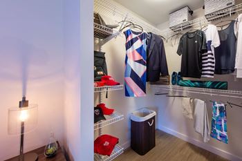 A room with a white wall and a shelf with clothes hanging on it.