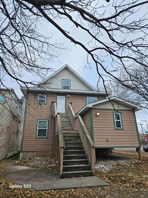 Saint Paul apartment for rent - A house with a brown siding and a white door is surrounded by bare trees.