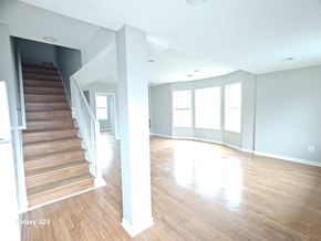 Saint Paul apartment for rent - A spacious room with wooden floors and a staircase leading to another level.