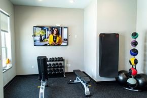 Waukee apartment for rent - a home gym with weights and a tv on the wall