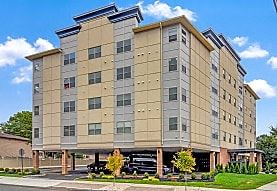Elizabeth apartment for rent - A large tan and brown building with a parking lot in front.