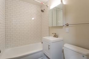 Denver apartment for rent - A white bathroom with a white tub, sink, and toilet.