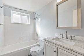 Denver apartment for rent - A white bathroom with a tub, toilet and sink.