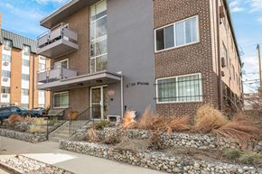 Denver apartment for rent - A modern brick building with a balcony and a stone wall in front.