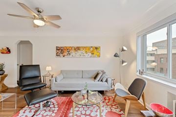 Denver apartment for rent - A living room with a grey couch, a black chair, a glass table and a red and white rug.