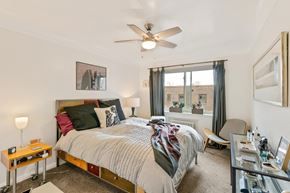 Denver apartment for rent - A bedroom with a bed, chair, and a ceiling fan.