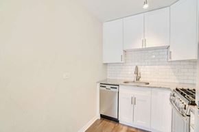 Denver apartment for rent - A kitchen with white cabinets and a white tiled backsplash.