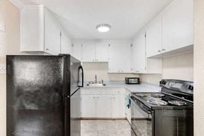 Denver apartment for rent - a kitchen with white cabinets and a black refrigerator