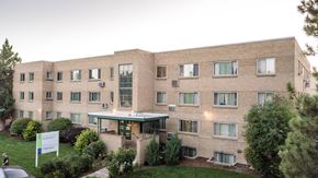 Denver apartment for rent - a large brick building with a green yard in front of it