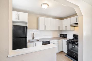 Denver apartment for rent - A kitchen with white cabinets and black appliances.